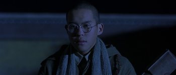 Movie still from “Kundun” (1997), directed by Martin Scorsese – A man wearing glasses and a scarf is looking to his left; Close Up shot, Low angle