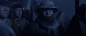 Movie still from “Kundun” (1997), directed by Martin Scorsese – A man wearing a hat and a scarf with a gun; Close Up shot, Low angle