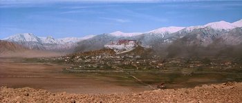 Movie still from “Kundun” (1997), directed by Martin Scorsese – A view of a mountain range with a large building in the background; Extreme Wide shot, High angle
