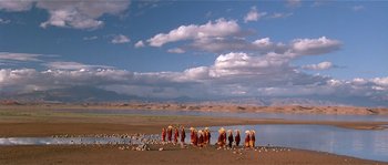 Movie still from “Kundun” (1997), directed by Martin Scorsese – A group of people standing next to a body of water; Extreme Wide shot, High angle