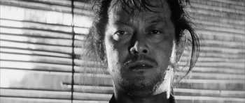 Movie still from “Black Cat” (1968), directed by Kaneto Shindô – Black and white photograph of a man's face in front of a window; Close Up shot, Low angle