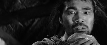 Movie still from “Black Cat” (1968), directed by Kaneto Shindô – A black and white photo of a man with long hair; Extreme Close Up shot, Low angle