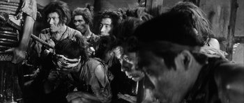 Movie still from “Black Cat” (1968), directed by Kaneto Shindô – A group of people sitting on the ground; Medium shot, Low angle