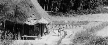 Movie still from “Black Cat” (1968), directed by Kaneto Shindô – An old photo of a man walking in front of a hut; Extreme Wide shot, High angle