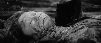 Movie still from “Black Cat” (1968), directed by Kaneto Shindô – A black and white photo of a black cat next to a doll head; Close Up shot, High angle