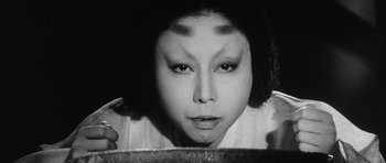 Movie still from “Black Cat” (1968), directed by Kaneto Shindô – A black - and - white photo of a woman smoking a cigarette; Close Up shot, Overhead angle