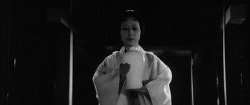 Movie still from “Black Cat” (1968), directed by Kaneto Shindô – A woman in a white robe holding a white object; Medium shot, Low angle