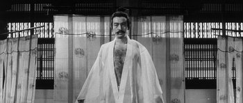 Movie still from “Black Cat” (1968), directed by Kaneto Shindô – A black and white photo of a man in a robe; Medium shot, Low angle