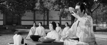 Movie still from “Black Cat” (1968), directed by Kaneto Shindô – A group of people sitting around a table; Medium shot, Over the shoulder angle