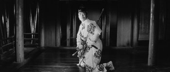 Movie still from “Black Cat” (1968), directed by Kaneto Shindô – A man kneeling on the ground holding a sword; Medium shot, Low angle