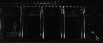 Movie still from “Black Cat” (1968), directed by Kaneto Shindô – A black - and - white photo of two pillars in the dark; Extreme Wide shot, Low angle