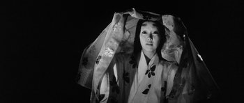 Movie still from “Black Cat” (1968), directed by Kaneto Shindô – A woman in a kimono is holding a veil over her head; Close Up shot, Low angle