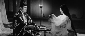 Movie still from “Black Cat” (1968), directed by Kaneto Shindô – A man and a woman sitting in a room; Medium shot, Over the shoulder angle