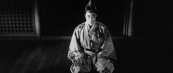 Movie still from “Black Cat” (1968), directed by Kaneto Shindô – A man in a kimono sitting on the ground; Medium shot, High angle