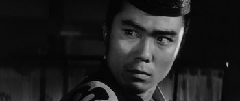 Movie still from “Black Cat” (1968), directed by Kaneto Shindô – A man's face in black - and - white photo; Close Up shot, Over the shoulder angle