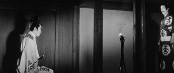 Movie still from “Black Cat” (1968), directed by Kaneto Shindô – A black and white photo of a room with a lamp; Medium shot, Low angle