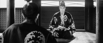 Movie still from “Black Cat” (1968), directed by Kaneto Shindô – A man sitting in front of a mirror wearing a kimono; Medium shot, Over the shoulder angle