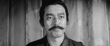 Movie still from “Black Cat” (1968), directed by Kaneto Shindô – A black and white photo of a man with a mustache; Close Up shot, Low angle