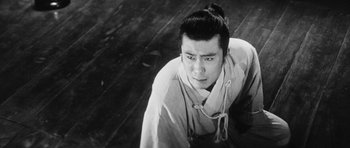 Movie still from “Black Cat” (1968), directed by Kaneto Shindô – A man in a white shirt is looking at the camera; Close Up shot, High angle