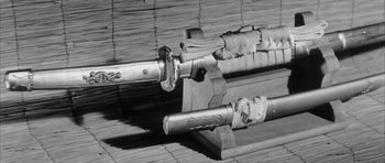 Movie still from “Black Cat” (1968), directed by Kaneto Shindô – A pair of swords sitting on top of a wooden bench; Extreme Close Up shot, High angle