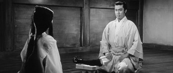 Movie still from “Black Cat” (1968), directed by Kaneto Shindô – A man sitting on the ground in front of another man; Medium shot, Over the shoulder angle