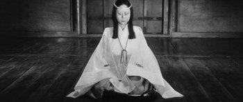 Movie still from “Black Cat” (1968), directed by Kaneto Shindô – A woman sitting on the ground wearing a kimono; Medium shot, High angle