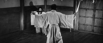 Movie still from “Black Cat” (1968), directed by Kaneto Shindô – A woman in a white robe is standing in front of a man in a white robe; Wide shot, Low angle