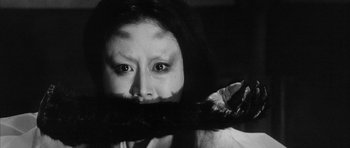 Movie still from “Black Cat” (1968), directed by Kaneto Shindô – A young woman with a long black hair covering her mouth; Close Up shot, Over the shoulder angle
