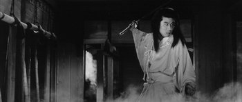 Movie still from “Black Cat” (1968), directed by Kaneto Shindô – A man holding a sword in front of a wall; Medium shot, Low angle