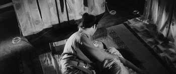 Movie still from “Black Cat” (1968), directed by Kaneto Shindô – An older man and a younger man are lying on a bed; Medium shot, High angle