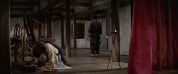 Movie still from “Kwaidan” (1964), directed by Masaki Kobayashi – A man holding a sword while standing in a room; Wide shot, Over the shoulder angle