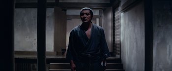 Movie still from “Kwaidan” (1964), directed by Masaki Kobayashi – A man wearing a black robe standing in a hallway; Medium shot, Low angle