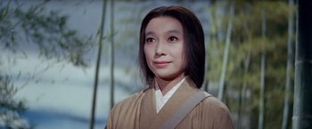 Movie still from “Kwaidan” (1964), directed by Masaki Kobayashi – A woman wearing a tan robe standing in front of bamboo trees; Close Up shot, Low angle