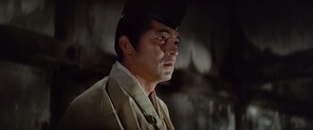 Movie still from “Kwaidan” (1964), directed by Masaki Kobayashi – A person wearing a suit and hat; Close Up shot, Low angle