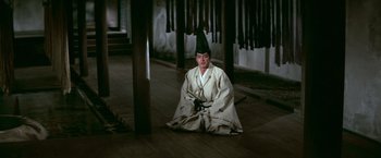 Movie still from “Kwaidan” (1964), directed by Masaki Kobayashi – A man sitting on the ground wearing a white robe; Wide shot, High angle