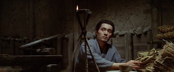 Movie still from “Kwaidan” (1964), directed by Masaki Kobayashi – A man sitting in front of a lit candle; Medium shot, Low angle
