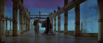 Movie still from “Kwaidan” (1964), directed by Masaki Kobayashi – Two people dressed in kimonos standing in front of a wooden fence; Extreme Wide shot, Low angle