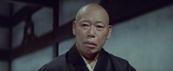 Movie still from “Kwaidan” (1964), directed by Masaki Kobayashi – An older man wearing a black kimono and a black robe; Close Up shot, Low angle