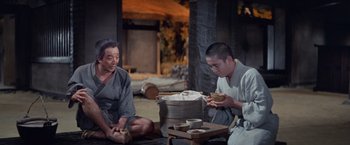 Movie still from “Kwaidan” (1964), directed by Masaki Kobayashi – Two men sitting on the ground eating food; Medium shot, High angle
