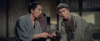 Movie still from “Kwaidan” (1964), directed by Masaki Kobayashi – Two asian men are looking at a cell phone; Medium shot, Low angle