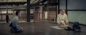 Movie still from “Kwaidan” (1964), directed by Masaki Kobayashi – A man sitting on a wooden floor in front of an open window; Wide shot, High angle