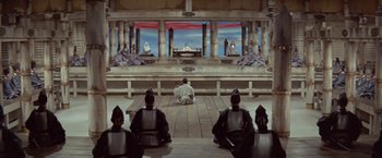 Movie still from “Kwaidan” (1964), directed by Masaki Kobayashi – A group of men sitting on a platform in front of a stage; Extreme Wide shot, High angle