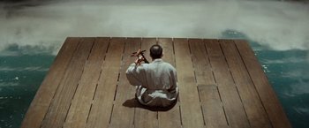Movie still from “Kwaidan” (1964), directed by Masaki Kobayashi – A man sitting on the ground holding a wooden object; Extreme Wide shot, High angle