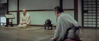 Movie still from “Kwaidan” (1964), directed by Masaki Kobayashi – A man sitting on the ground in front of a pot; Wide shot, Over the shoulder angle