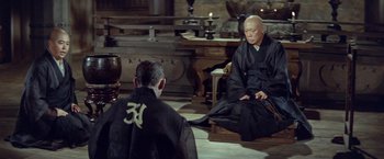 Movie still from “Kwaidan” (1964), directed by Masaki Kobayashi – Two men sitting on the ground in a room; Wide shot, High angle