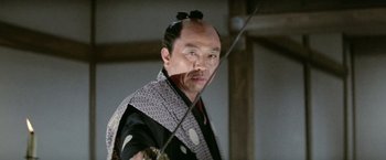Movie still from “Kwaidan” (1964), directed by Masaki Kobayashi – A man in a samurai outfit holding a sword in his hand; Close Up shot, Low angle