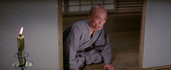 Movie still from “Kwaidan” (1964), directed by Masaki Kobayashi – An older man in a kimono sitting on the ground; Medium shot, High angle