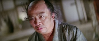 Movie still from “Kwaidan” (1964), directed by Masaki Kobayashi – An older man with long black hair wearing a gray robe; Close Up shot, Low angle