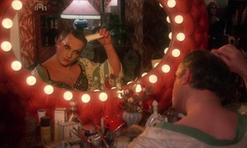 Movie still from “La Cage aux Folles” (1978), directed by Édouard Molinaro – A woman in front of a mirror with a brush in her mouth; Medium shot, Over the shoulder angle