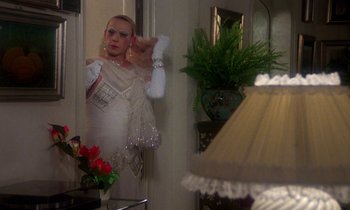 Movie still from “La Cage aux Folles” (1978), directed by Édouard Molinaro – A woman in a white dress in front of a bathroom mirror; Medium shot, Over the shoulder angle